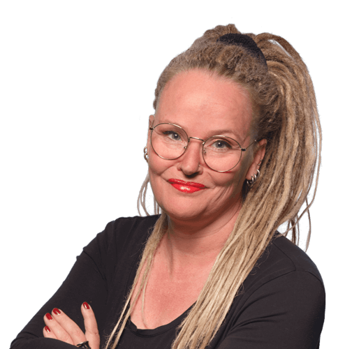 Portrait of Anne Bovelett, a smiling woman with a big blonde ponytail, round glasses and shiny red lipstick, crossing her arms in a relaxed manner.